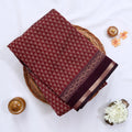 Semi Chanderi saree with delicate printed motifs in maroon and purple folded display top view with decorative border.