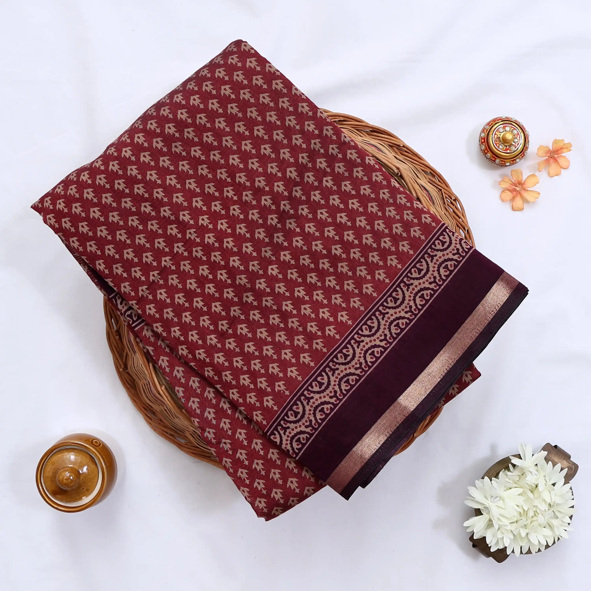 Semi Chanderi saree with delicate printed motifs in maroon and purple folded display top view with decorative border.