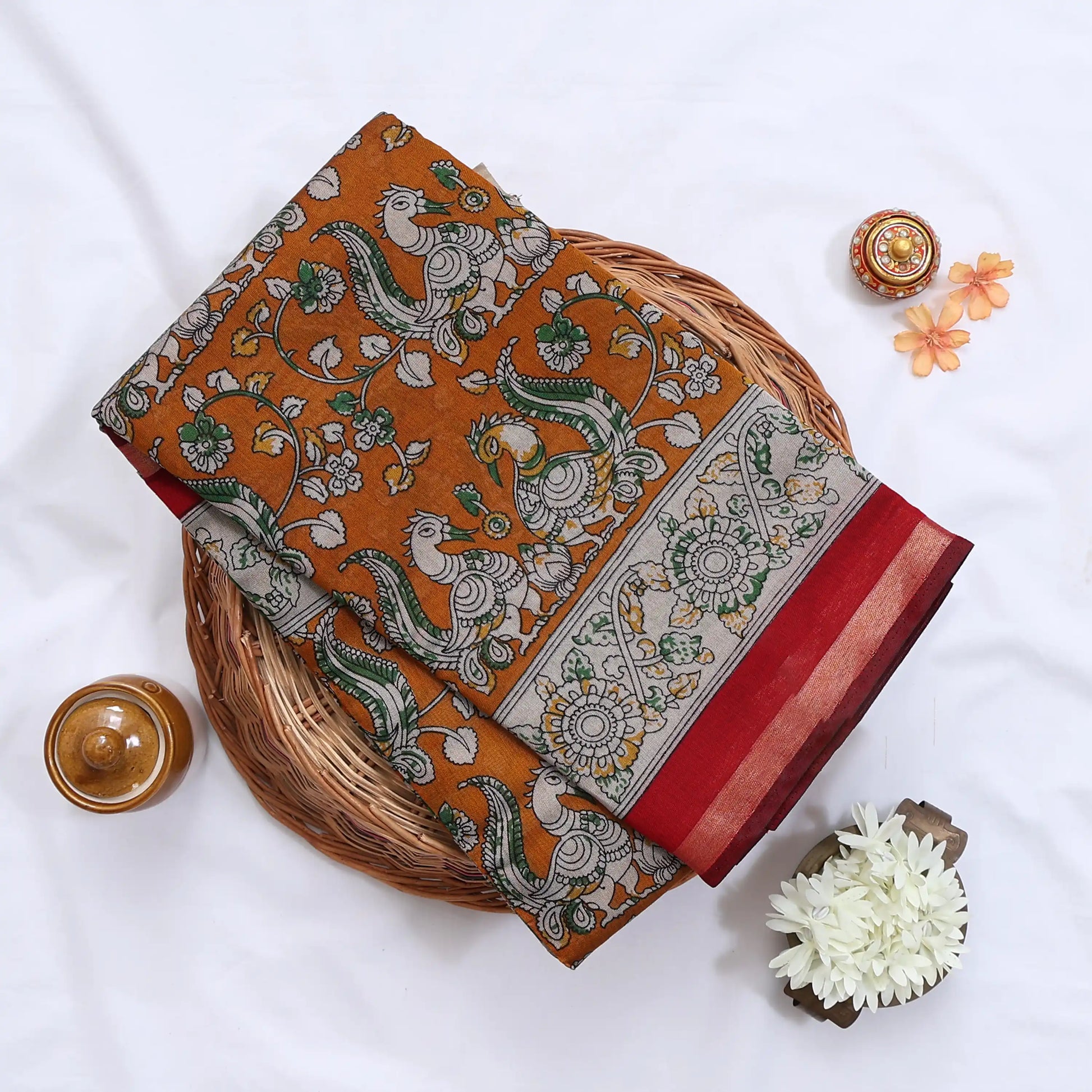 Orange Semi Chanderi saree with peacock floral print and contrast woven border folded flat lay display.