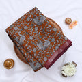 Semi Chanderi saree with white floral and peacock print on orange fabric maroon woven border folded top view on wicker tray.