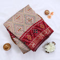 Cream Semi Chanderi saree with bandhani dot print and deer & floral woven border folded flat lay display.