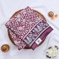 Semi Chanderi saree with floral and peacock print in pink and purple folded top view with zari border.