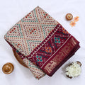 Cream Semi Chanderi saree with bandhani dot print and deer & floral woven border folded flat lay display.