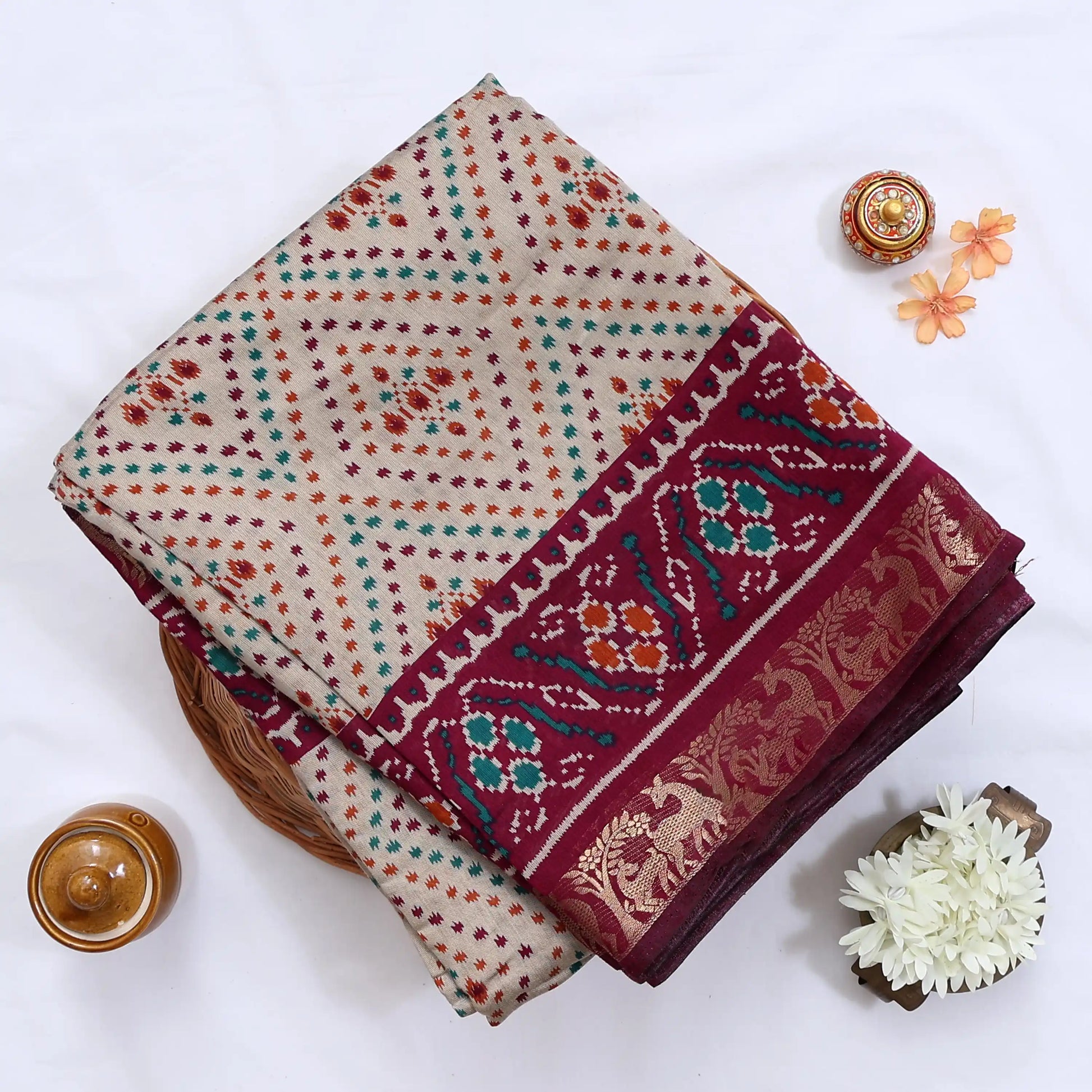Cream Semi Chanderi saree with bandhani dot print and deer & floral woven border folded flat lay display.