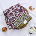 Semi Chanderi saree with floral and peacock print in green and purple folded top view with zari border.