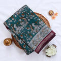 Teal Semi Chanderi saree with floral peacock print and contrast woven border folded flat lay display.