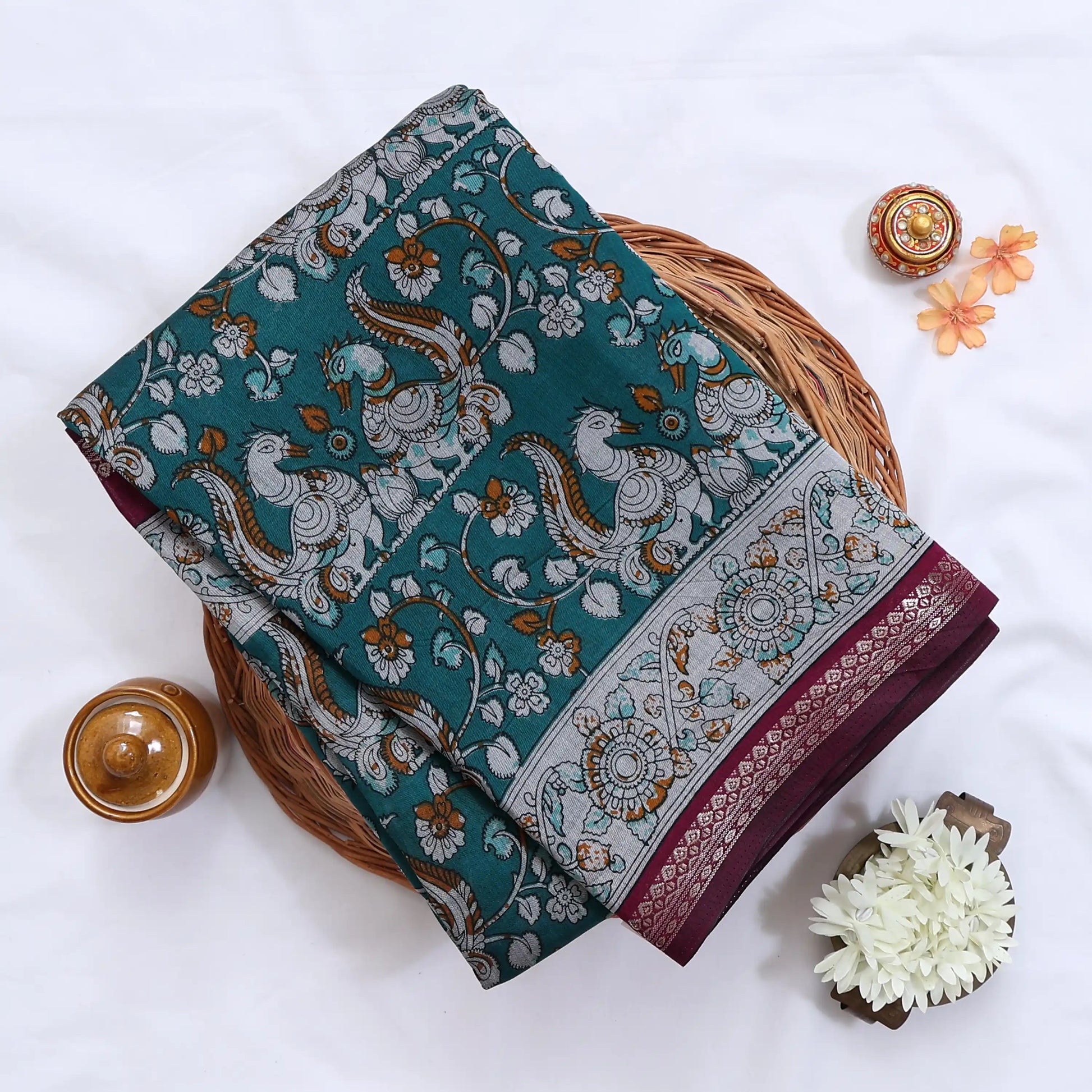 Teal Semi Chanderi saree with floral peacock print and contrast woven border folded flat lay display.