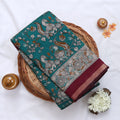 Teal Semi Chanderi saree with peacock floral print and contrast woven border folded flat lay display.