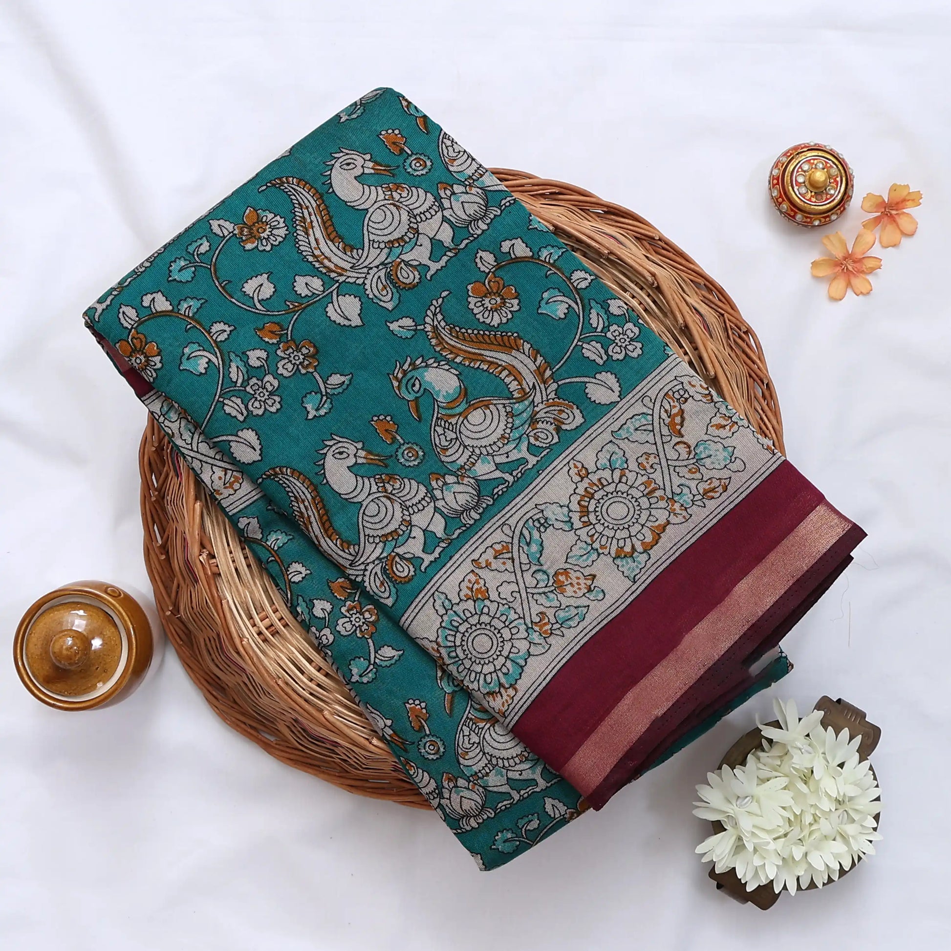 Teal Semi Chanderi saree with peacock floral print and contrast woven border folded flat lay display.