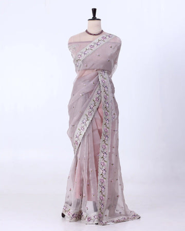 A light pink and lavender organza saree with floral embroidery and a matching border