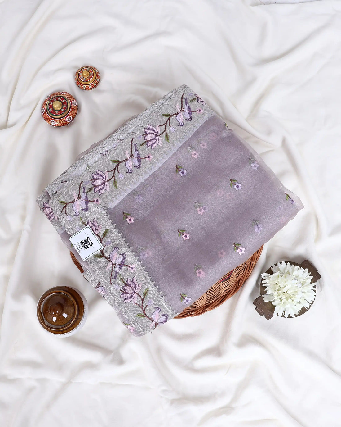 A light pink and lavender organza saree with floral embroidery and a matching border
