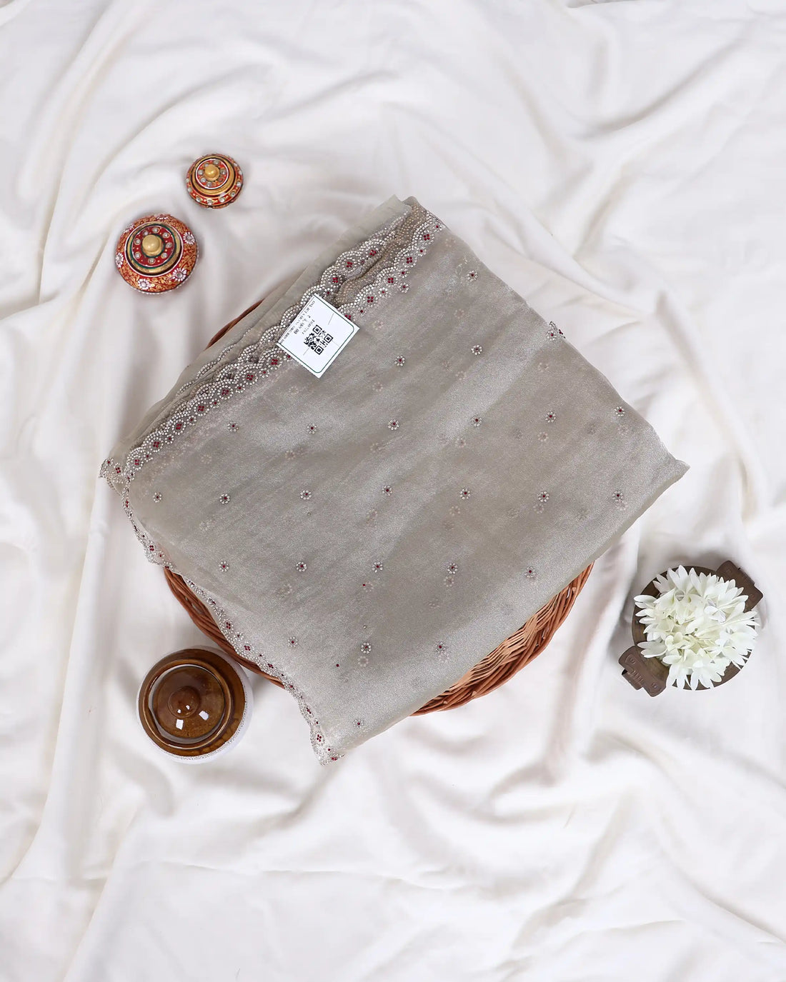 A light beige and pink sheer saree  features delicate silver embroidery along the border and a matching blouse.