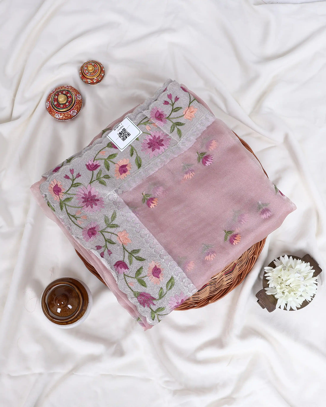 A folded dusty pink embroidered dupatta with floral patterns and a gray border