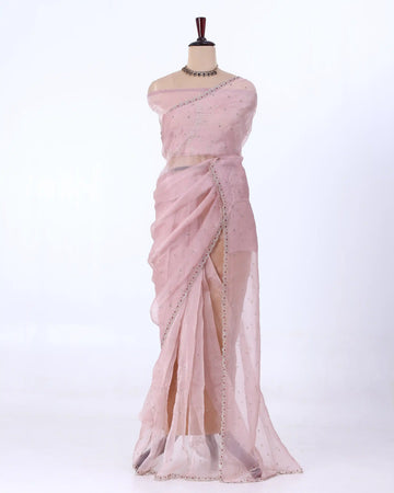 A light pink saree with silver mirror work and bead borders
