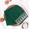 A folded dark green sareewith a decorative border pattern