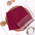 A folded purple mysore silk saree ifeatures a beige border with woven stripes.
