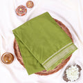 An olive green folded mysole silk saree  features a decorative border with white and green embroidery 