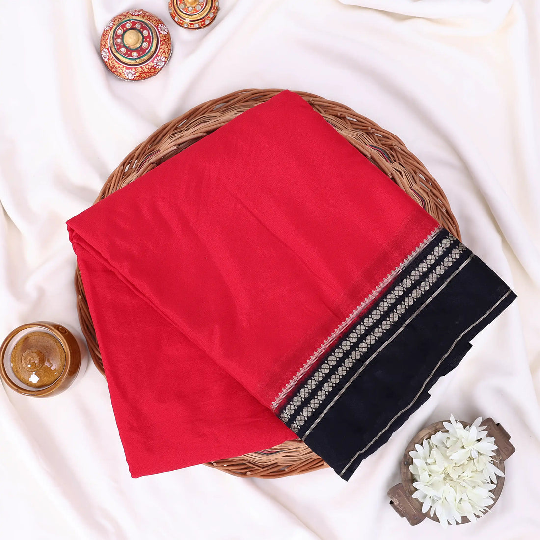 A red and black saree featuring a black blouse with gold stripes and a matching black patterned pallu with gold detailing