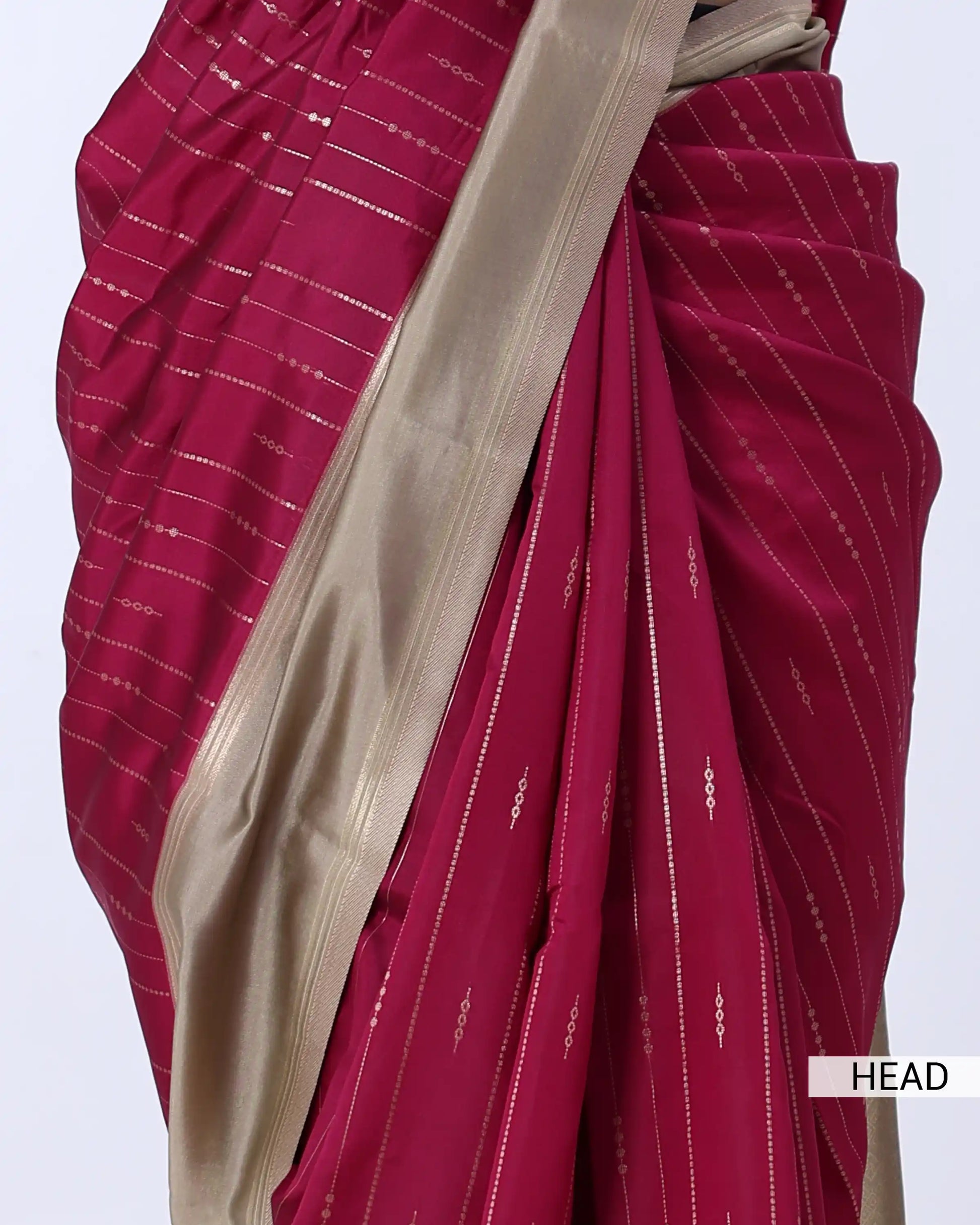 A close-up of a draped sari in deep magenta pink with thin white stripes and a wide beige border