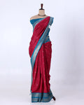 A red and blue saree has a deep red body with a blue border and small metallic motifs, and is paired with a matching blue blouse.