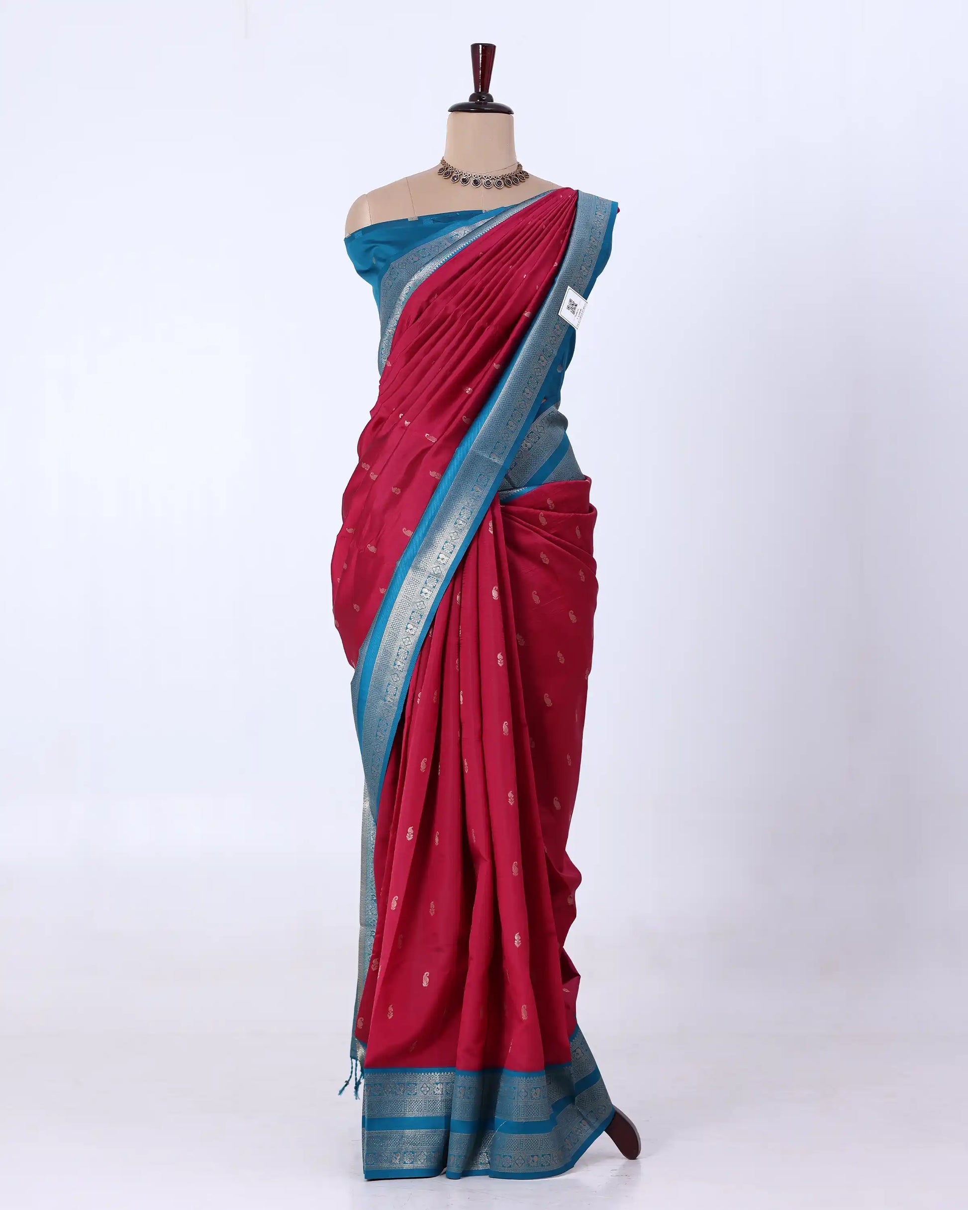 A red and blue saree has a deep red body with a blue border and small metallic motifs, and is paired with a matching blue blouse.