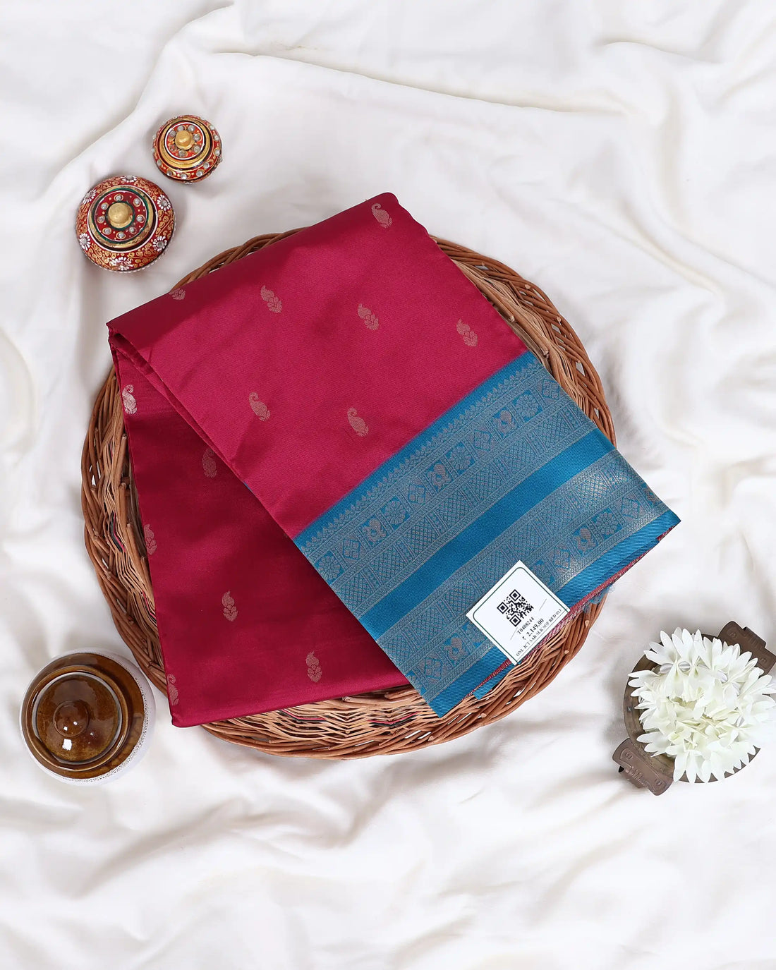 A red and blue saree has a deep red body with a blue border and small metallic motifs, and is paired with a matching blue blouse.