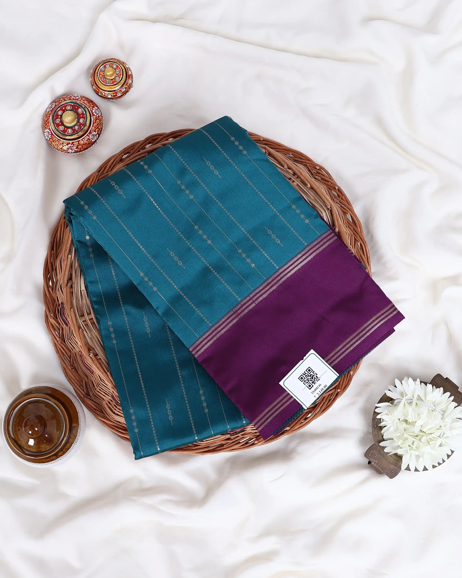 A folded teal and purple silk saree with gold zari stripes