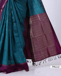 A close-up of a teal and deep purple saree with metallic gold zari detailing