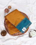 A folded mustard yellow and teal saree 