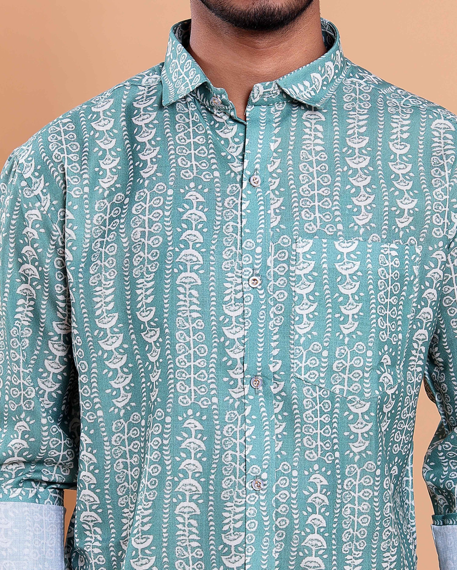 Teal patterned shirt worn by a person on a beige background