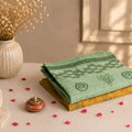 Folded Bengal Cotton Saree In  Green & Yellow With Woven Border Patterns And Floral Details Close Up Display